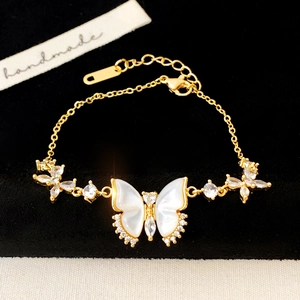 Detail eines eleganten Gold-Armbands mit Schmetterling, Muscheleinlage und Zirkonia-Steinen