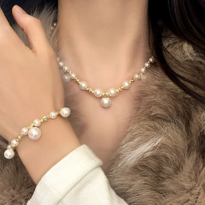 Parure collier et bracelet en perles avec détails dorés portée avec manteau en fourrure