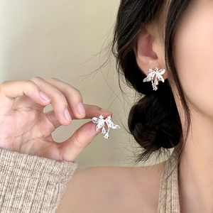 Elegant silver bow earrings with sparkling zircon crystals worn by a model
