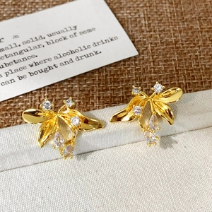 Macro shot of gold zircon petal earrings with teardrop stones on textured fabric