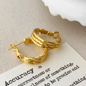 Detailed macro view of multi-layered gold-plated hoop earrings with textured weaving finish