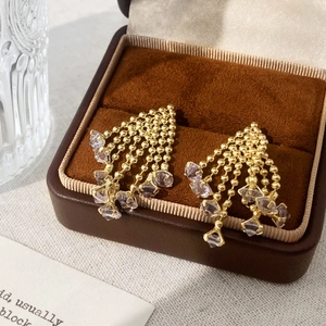 Close-up of gold tassel earrings with purple crystals in a velvet jewelry box