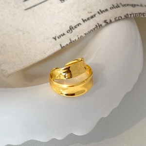 Gros plan d'une bague dorée ondulée à double couche avec ouverture réglable sur céramique
