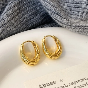 Detailed view of gold-plated twisted U-shape hoop earrings with a metallic spiral texture