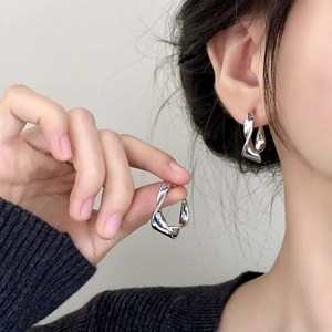 Elegant polished silver twisted geometric earrings worn with a black knit sweater