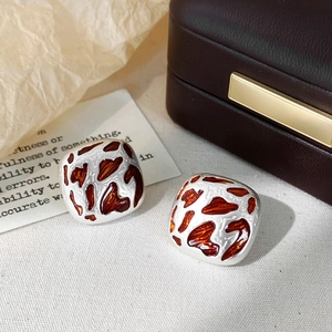Silver square stud earrings with leopard print enamel on a jewelry display stand