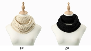Detail view of chunky cable knit infinity scarves in cream and black on mannequins