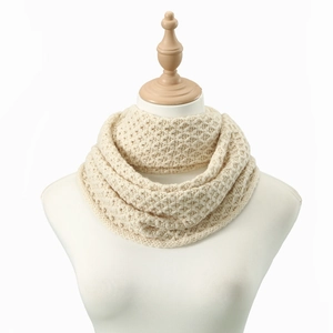 Macro detail of creamy white cable knit infinity scarf showing thick yarn texture
