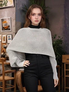 Detail of light grey knitted shrug featuring chunky textured stitching and a cropped fit
