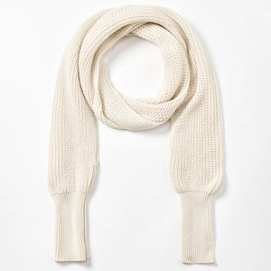 Close-up of thick beige knit texture and long ribbed cuffs on minimalist shawl