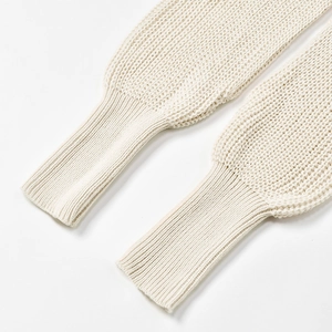 Macro detail of creamy white ribbed cuffs and thick knit texture on women's wrap sweater