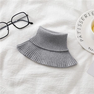 Detailed close-up of a grey ribbed knit neck warmer on a cozy white fabric background