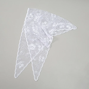 Detail of white lace triangle scarf featuring intricate cherry embroidery and scalloped edges