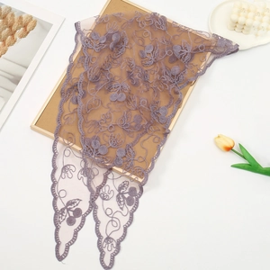Detail of purple lace triangle scarf with floral embroidery on wooden background