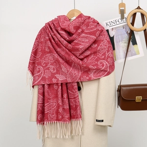 Detail of red paisley jacquard scarf with tassels paired with beige coat and brown bag