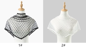 Close-up of black and white polka dot mesh shawl featuring lace trim and pompom edges