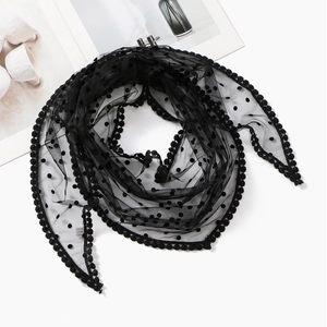 Detailed view of black polka dot mesh scarf with playful pom-pom decorative edges