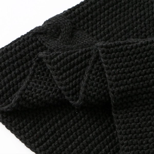 Detailaufnahme der dicken, groben Strickstruktur eines schwarzen Winter-Halswärmerschals.