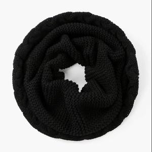 Detailansicht eines dicken schwarzen Strickschals mit warmem Zopfmuster und Textur