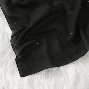 Detailed view of black square scarf featuring sparkling rhinestones on textured fabric