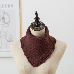 Détail d'un cache-cou en tricot marron foncé avec bordure en dentelle festonnée et maille épaisse