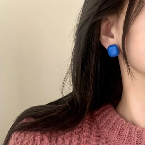 Close-up of elegant square blue stud earrings on model for a minimalist daily look