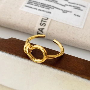 Minimalist gold knot open ring displayed on a wooden stand with elegant packaging
