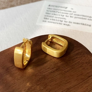 Close-up of golden geometric rectangle earrings with brushed matte finish on wood