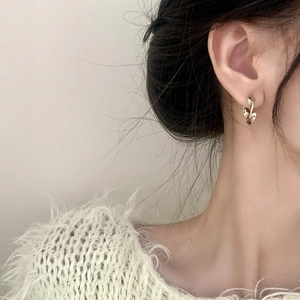 Boucles d'oreilles dorées torsadées de style vintage portées par un mannequin élégant