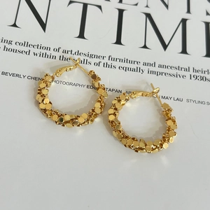 Macro shot of gold twist earrings with faceted glitter texture on fashion magazine