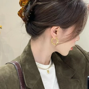 Elegant gold twisted hoop earrings with textured finish shown on model in profile