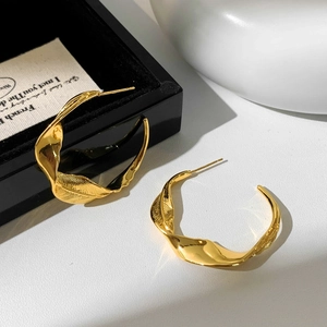 Dettaglio orecchini a foglia d'oro con pieghe metalliche intrecciate e finitura lucida