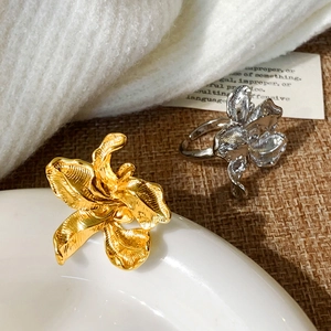Elegant gold and silver lily flower open rings with textured petals on white porcelain