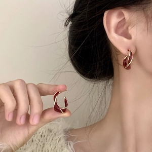 Close-up of elegant wine red enamel twisted hoop earrings with gold trim on model