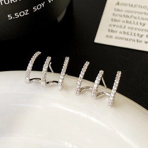 Detail shot of silver claw stud earrings with micro-set zircons on white ceramic