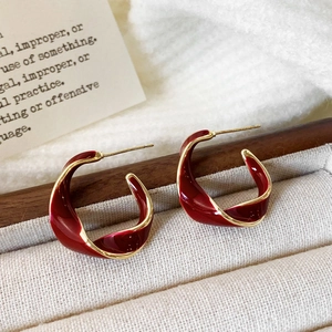 Macro shot of French retro red enamel twisted C-shape earrings in a velvet box