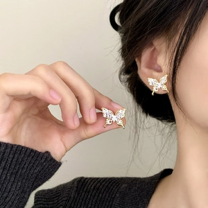 Elegant gold butterfly earrings with white zircon hollow lace design worn on earlobe
