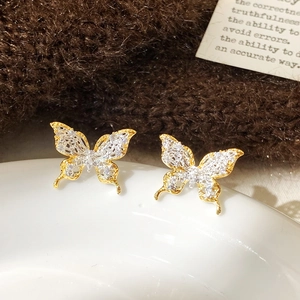 Detailed close-up of hollow lace butterfly earrings with gold plating and white crystals
