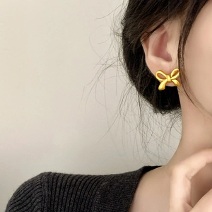 Matte gold bow earrings for women featuring a minimalist design on female ear
