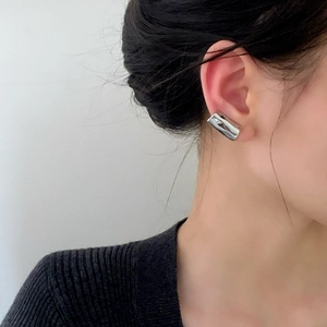 Close-up of minimalist silver liquid wave ear cuff on female model with mirror finish