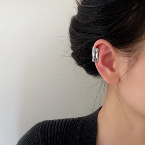 Silver liquid metal ear cuff with minimalist irregular lava design on earlobe