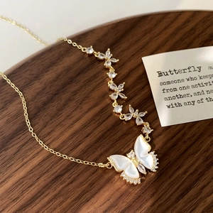 Détail du collier papillon doré avec ailes en nacre blanche et accents de zircone brillants