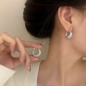 Silver twisted rope hoop earrings with minimalist croissant design on a model