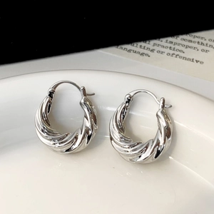 Detailed view of silver twisted rope hoop earrings on a minimalist ceramic tray