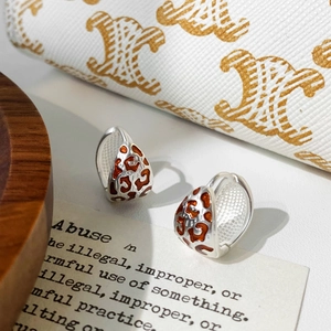 Detailed close-up of leopard print hoop earrings with dark red enamel and silver finish