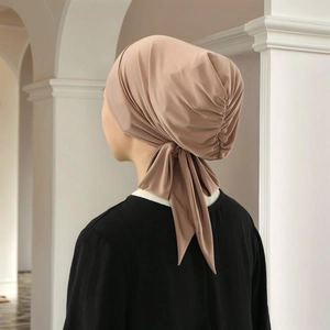 Detail of taupe pleated turban cap showing soft knit fabric and elegant back ties