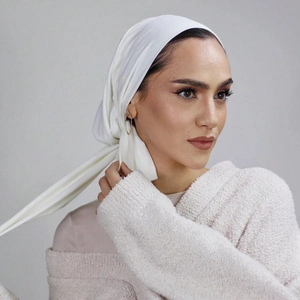 Detail of white pleated satin hijab headscarf with elegant gold chain earrings