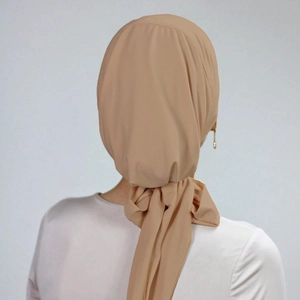 Close-up of beige pleated headscarf with ties showing soft fabric texture and draping