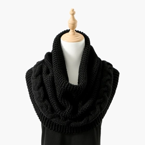 Detail eines schwarzen Strickschals mit Zopfmuster und dicker Textur auf einer Schneiderpuppe