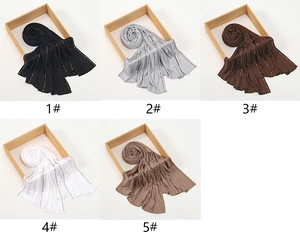 Detail view of five modal hijab colors featuring golden rhinestone patterns on wooden frames
